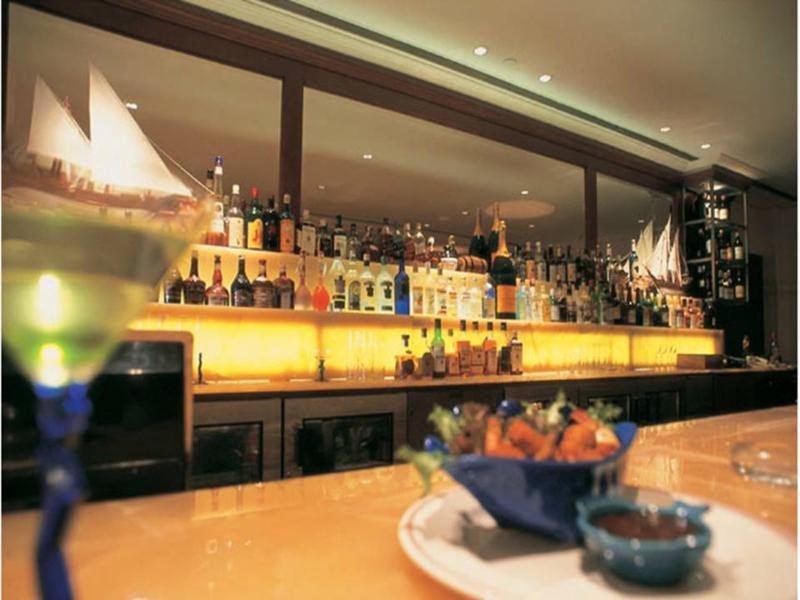 فندق ذا تاج محل تاور مومباي المظهر الخارجي الصورة The photo depicts a stylish bar setting. In the background, there is a well-stocked bar shelf lined with numerous bottles of various alcoholic beverages, illuminated by soft lighting that creates a warm ambiance. The countertop appears to be smooth a
