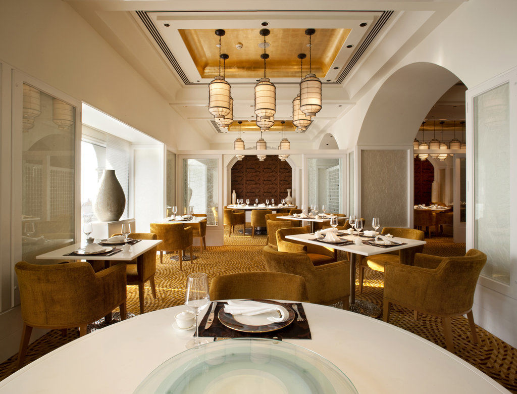 فندق ذا تاج محل تاور مومباي المظهر الخارجي الصورة The photo shows an elegantly designed restaurant interior. The space features stylish furnishings, including round tables topped with white tablecloths and plush, mustard-colored chairs. The ceiling has a decorative design, with pendant lights hangin
