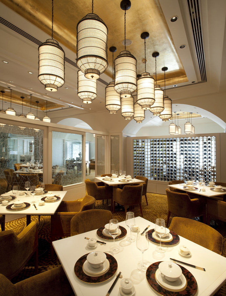 فندق ذا تاج محل تاور مومباي المظهر الخارجي الصورة The photo depicts an elegant restaurant interior. It features a sophisticated design with multiple hanging light fixtures that have a distinct, stylish appearance. The tables are round and set for dining, with neatly arranged plates and utensils. The