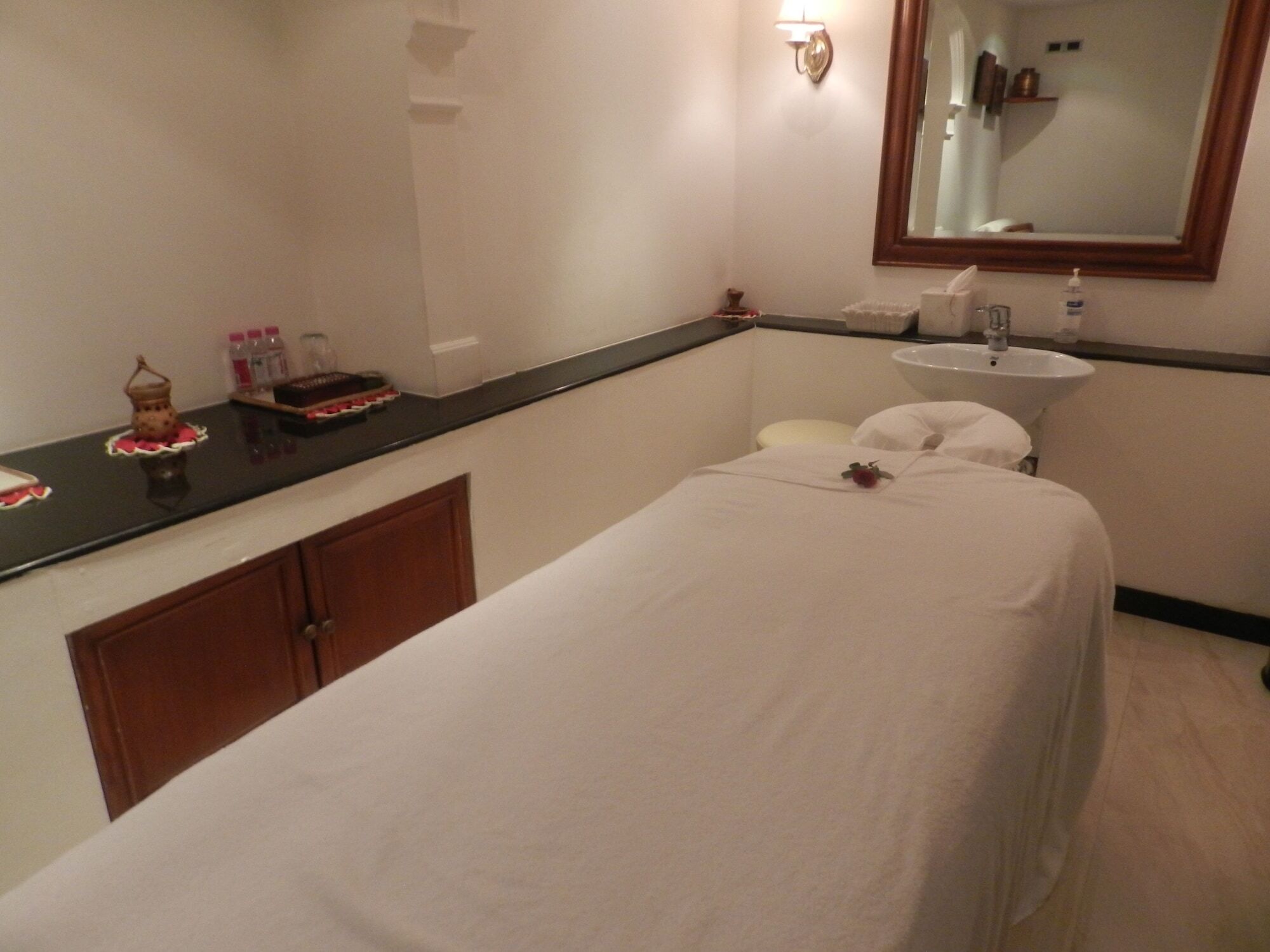فندق ذا تاج محل تاور مومباي المظهر الخارجي الصورة The photo shows a serene spa room designed for relaxation and treatments. In the center, there is a massage table covered with a white sheet. There is a small decorative item, possibly a flower, placed on the table. Alongside, a dark countertop displ